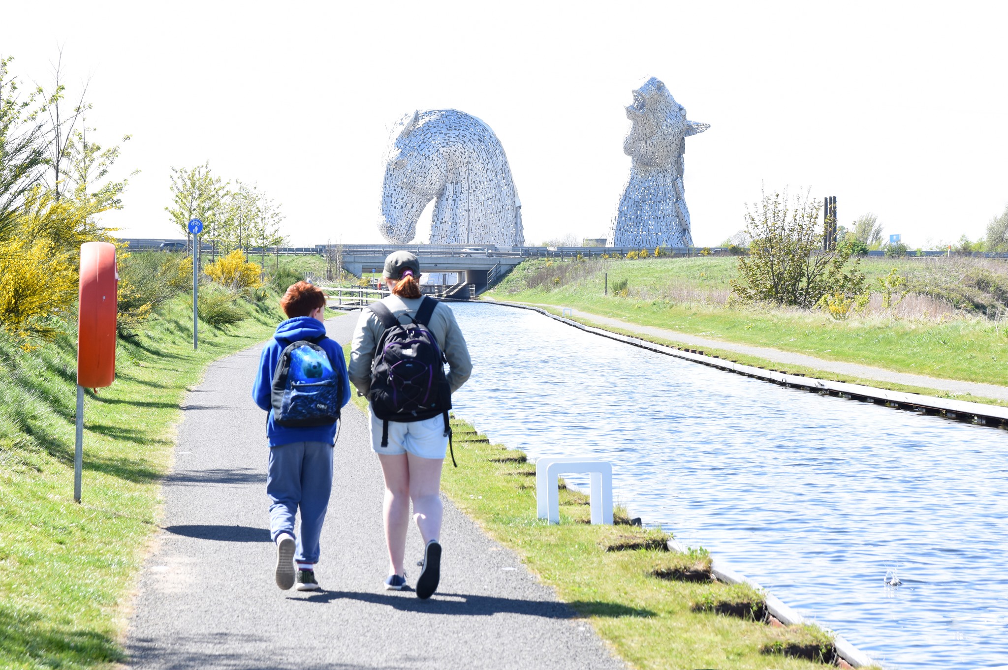 Two people walking along the canal to The Kelpies