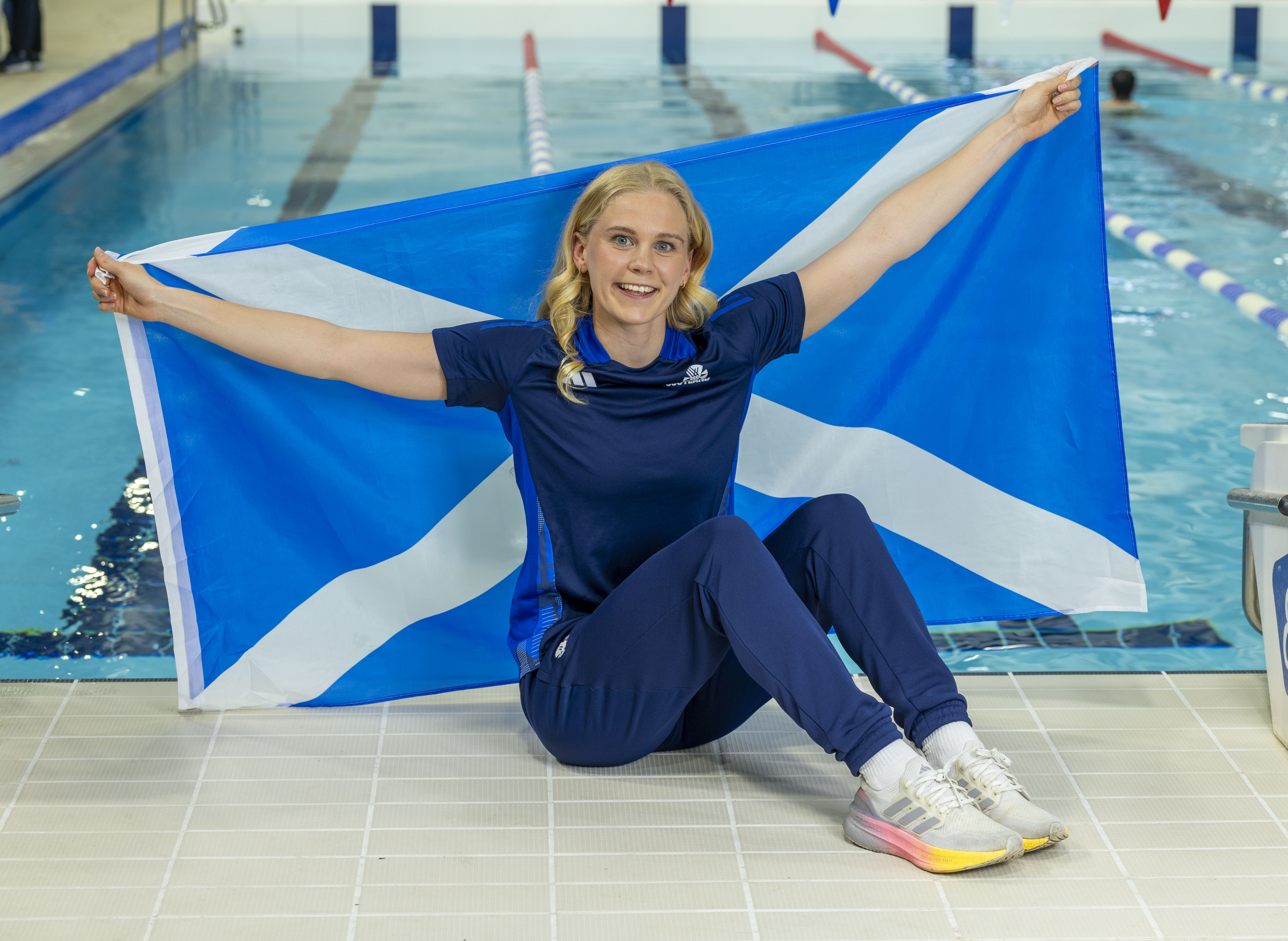 Lucy Hope with a Scotland flag sitting by a swimming pool